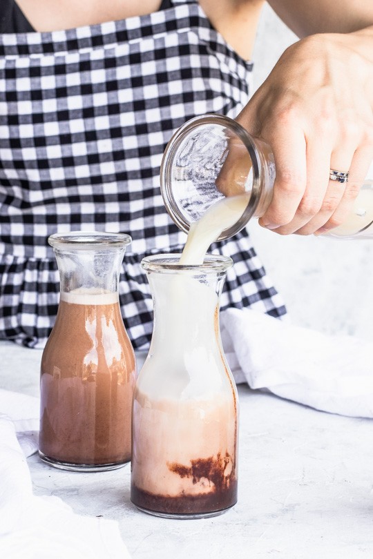 Freshly made peanut milk being poured into glass carafes with chocolate sauce to make Chocolate Peanut Milk