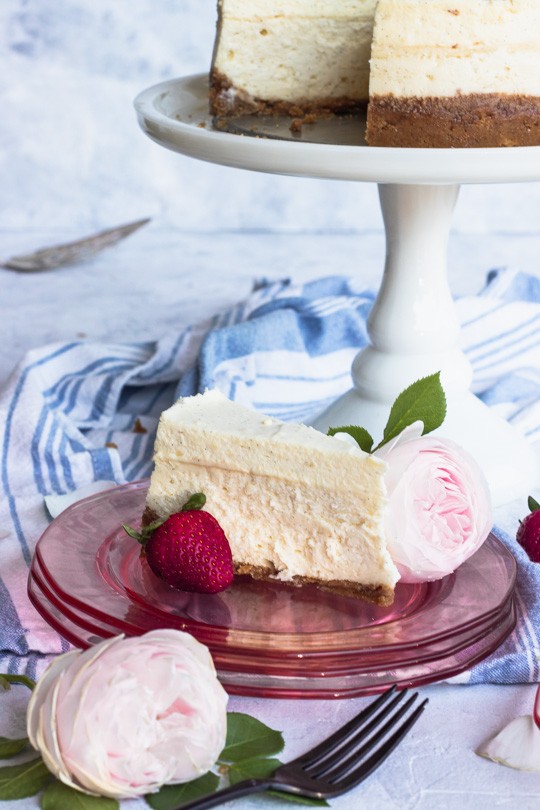 Slice of Vanilla Bean Cheesecake with Strawberry and Pink Rose Garnish