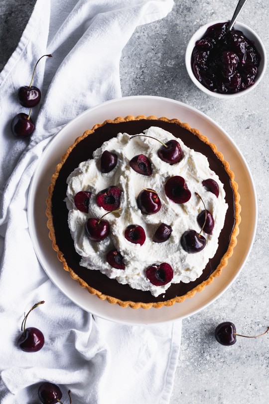 Chocolate Cherry Tart -- A delicate pastry case filled with a layer of sweet cherries and topped with chocolate ganache. Pile it high with whipped cream and top with more cherries. || Good Things Baking Co. #goodthingsbaking #chocolatecherry #darkchocolate #chocolateganache #chocolatetart #tartrecipe 