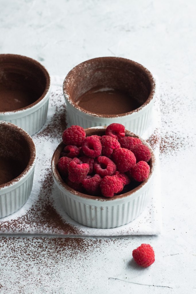 Ramekins dusted with cocoa powder and one filled with raspberries