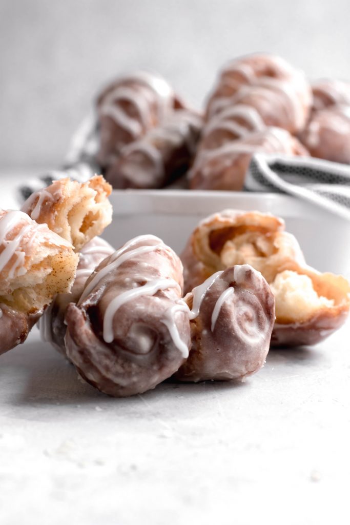 Cinnamon Roll Donuts -- Donut Twists in a pan with glaze drizzled over the top.