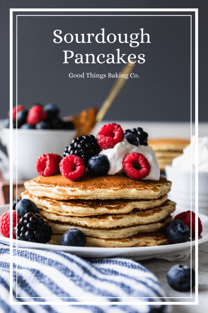 A stack of overnight sourdough pancakes piled high with whipping cream and berries.