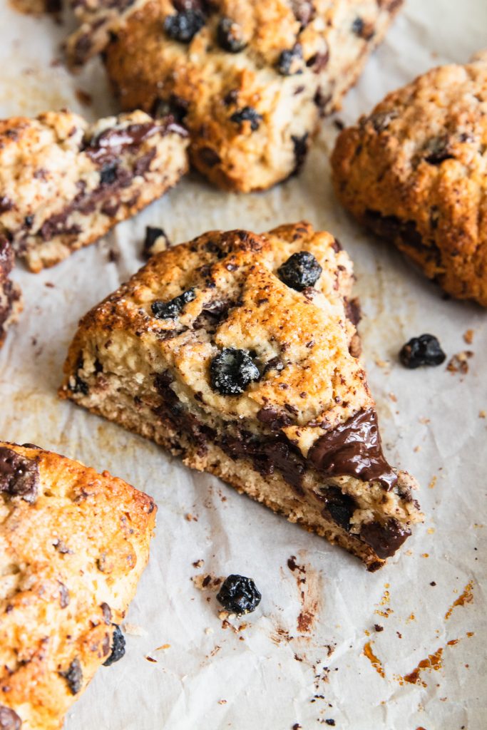 A close up of a scone filled with chunks of chocolate and blueberries