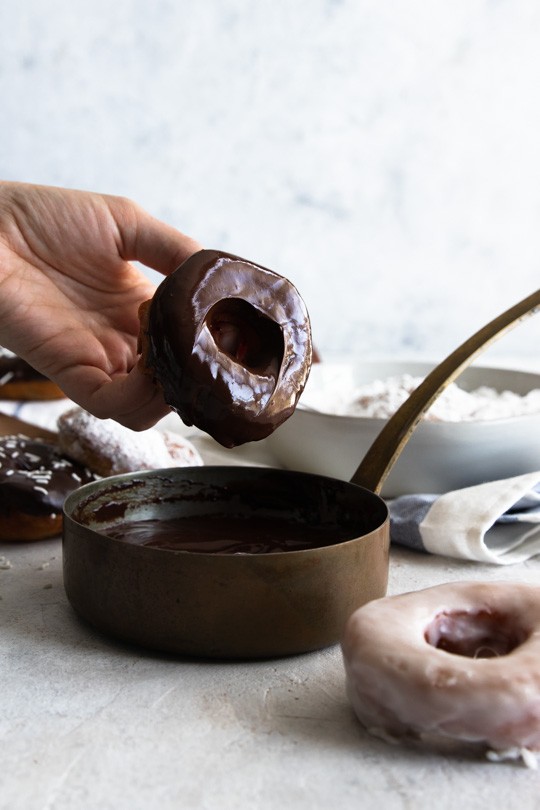Dipping a donut in the chocolate ganache glaze.