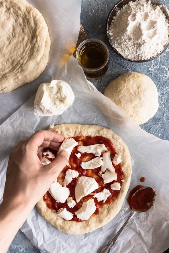 Pulled fresh mozzarella being put on a pizza
