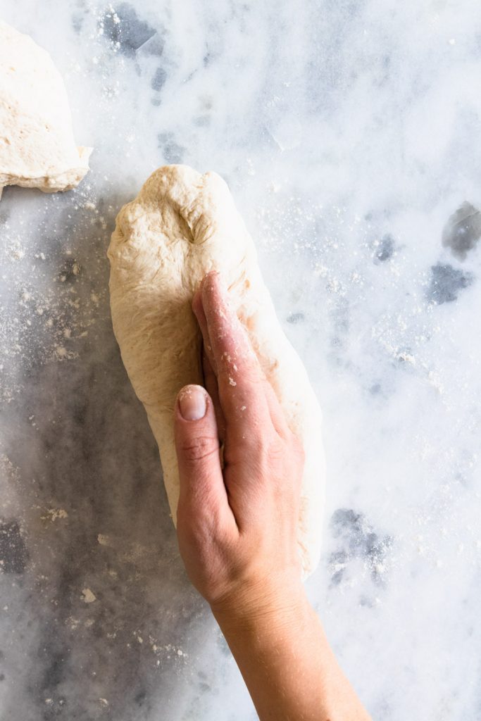 Step four for shaping baguettes: use the edge of your hand to press down the seam of the dough.