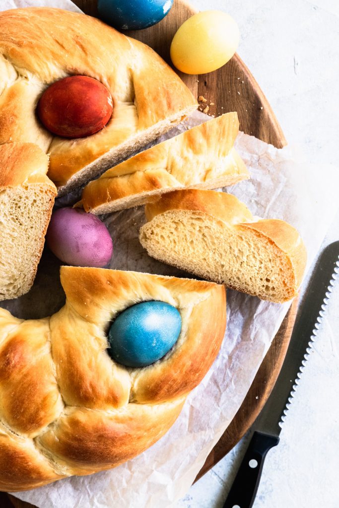 Slices of Pane di Pasqua, a braid circle loaf decorated on top with dyed Easter eggs.
