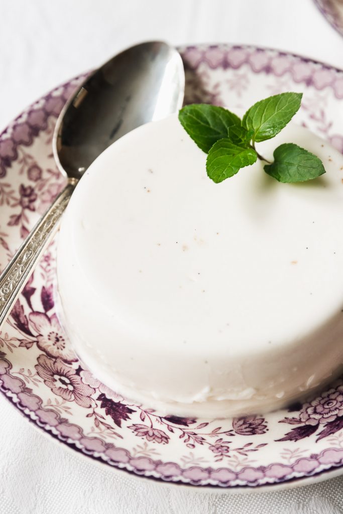 A close-up of a panna cotta garnised with a sprig of fresh mint.