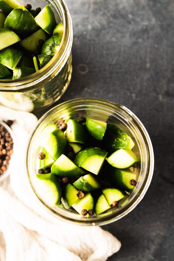 Pack the cucumbers a tightly as possible in the jar without smashing them, then sprinkle the peppercorns over them.