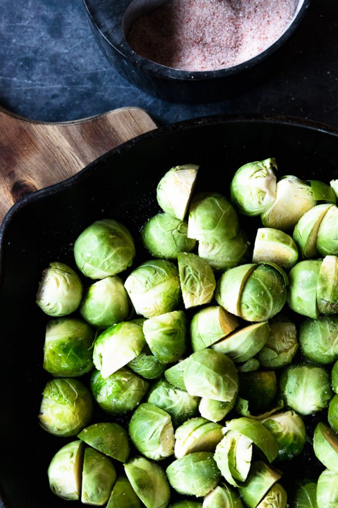 Adding the prepared brussels sprouts to a pan of hot bacon grease before searing them.