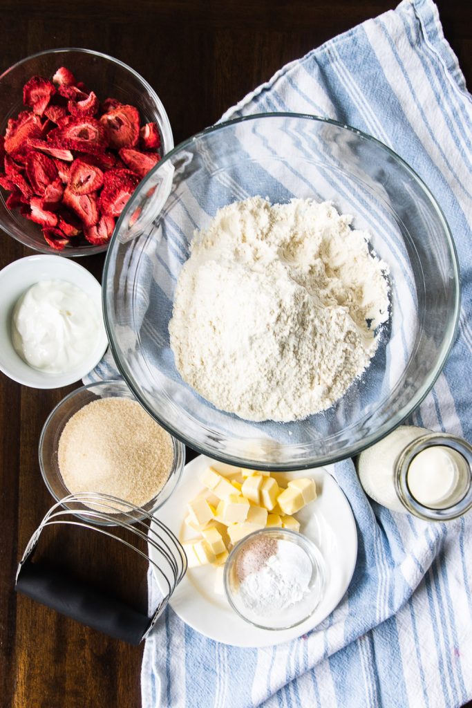 The ingredients for strawberry scones: flour, freeze dried strawberries, sour cream, sugar, butter, baking powder and soda, salt, and whipping cream.