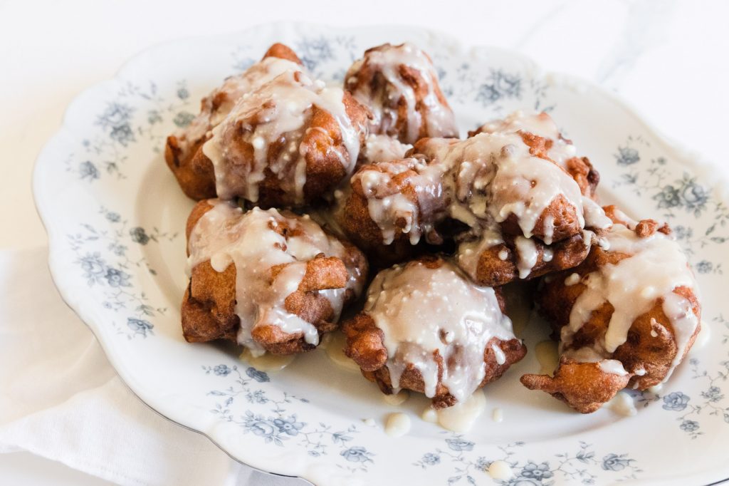 A plate of peach fritters, an easy and delicious summer recipe. They're golden brown with glaze drizzled over the top.