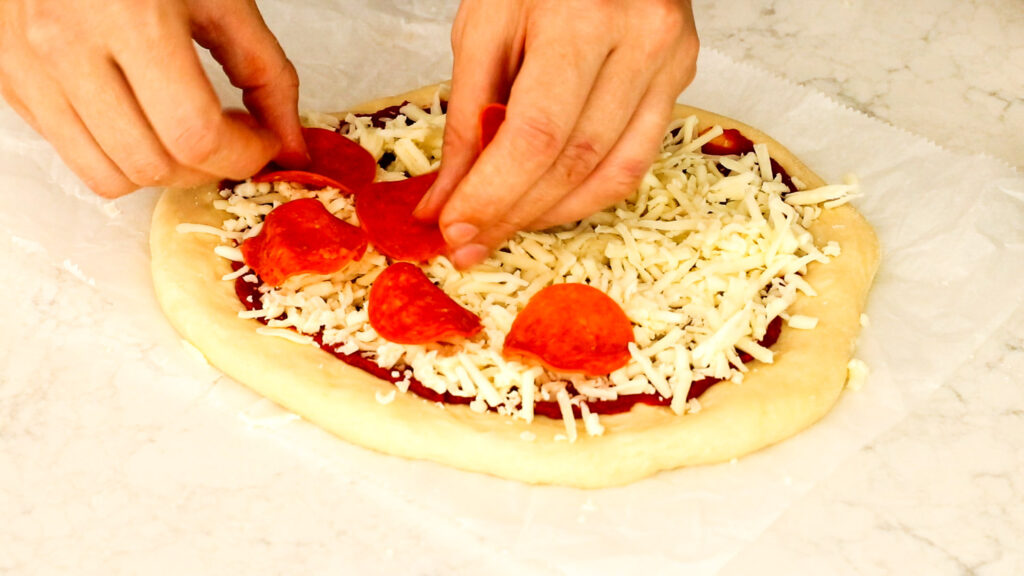 Add sauce, cheese, and toppings to the pizza.