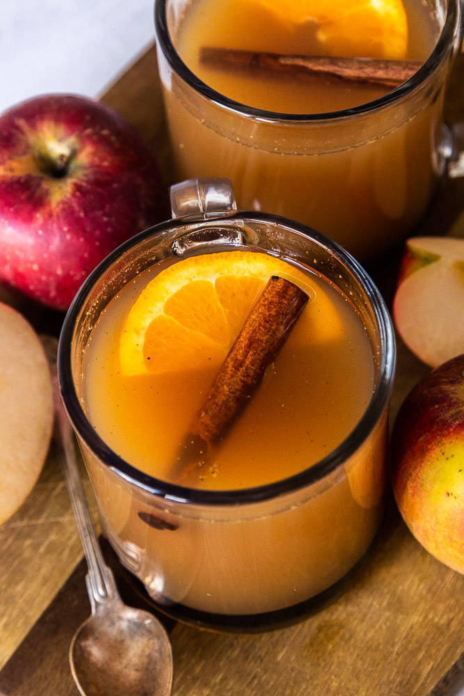 Chai Spice Apple Cider in a mug, topped with a slice of orange and a cinnamon stick.