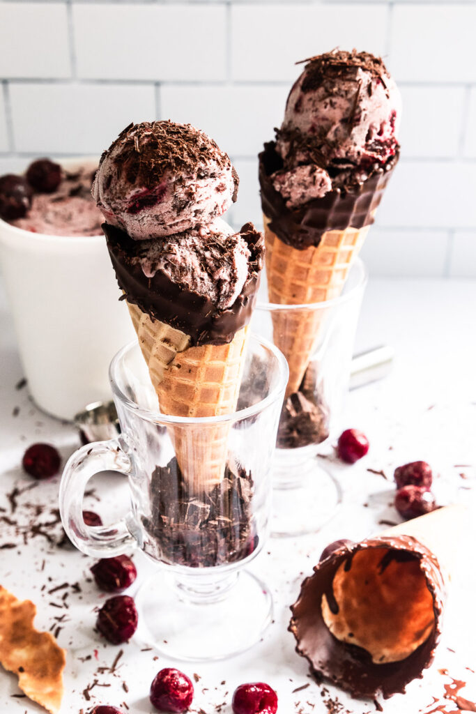 Scoops of black forest ice cream in chocolate dipped waffle cones.