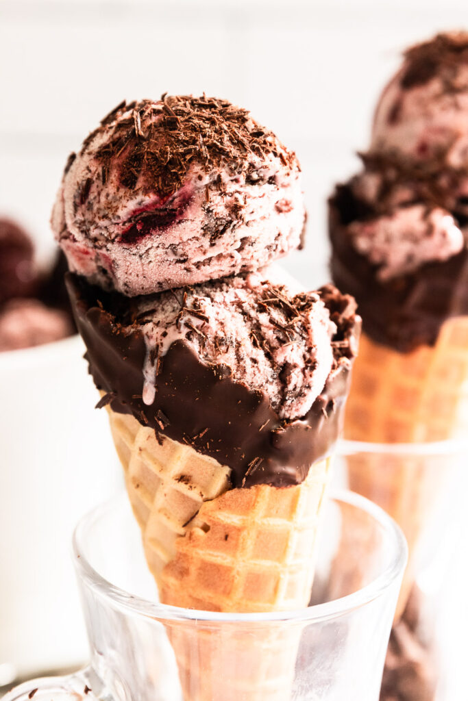 A dripping scoop of Black Forest ice cream in a cone.