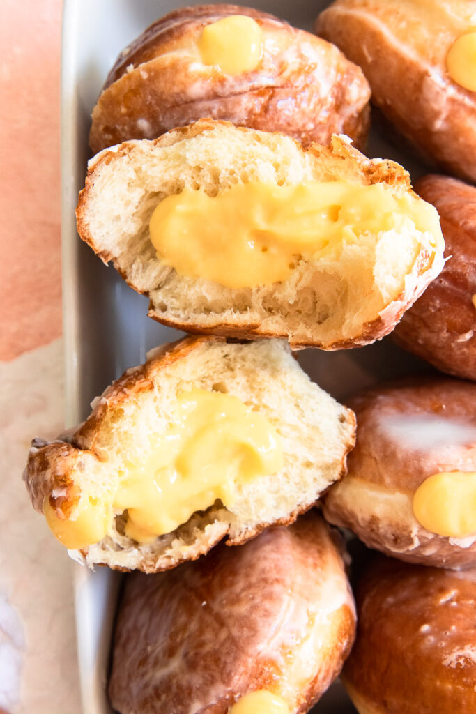 The inside of a fluffy glazed donut, filled with passion fruit pastry cream.