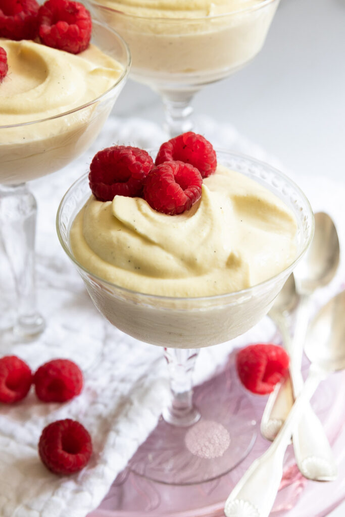 A cup of mousse, garnished with raspberries.
