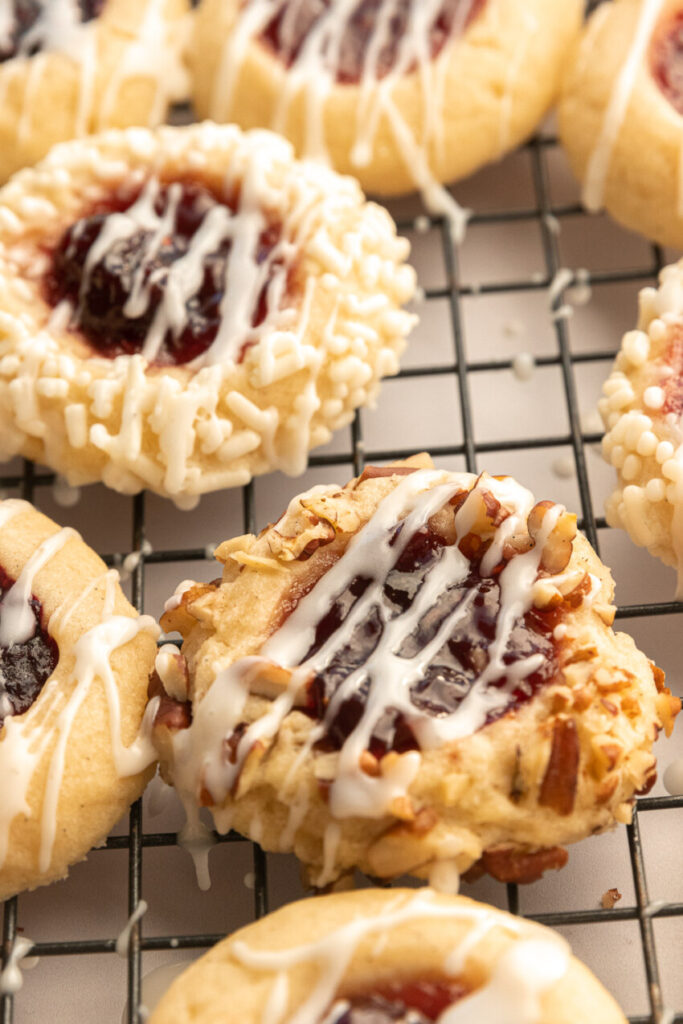 A thumbprint cookie rolled in chopped nuts, filled with jam, and drizzled with icing.