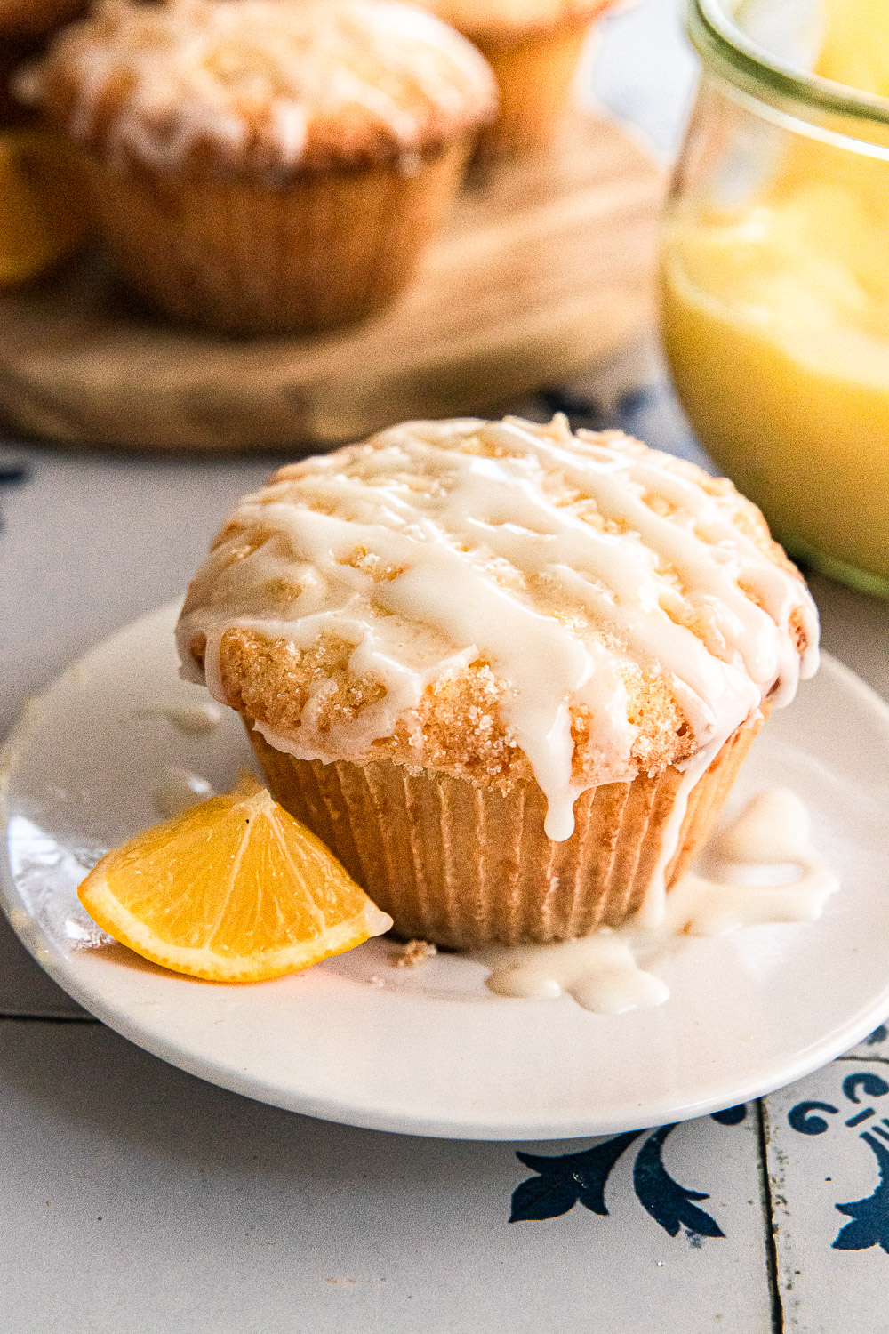 A lemon curd muffin on a plate with a wedge of lemon.
