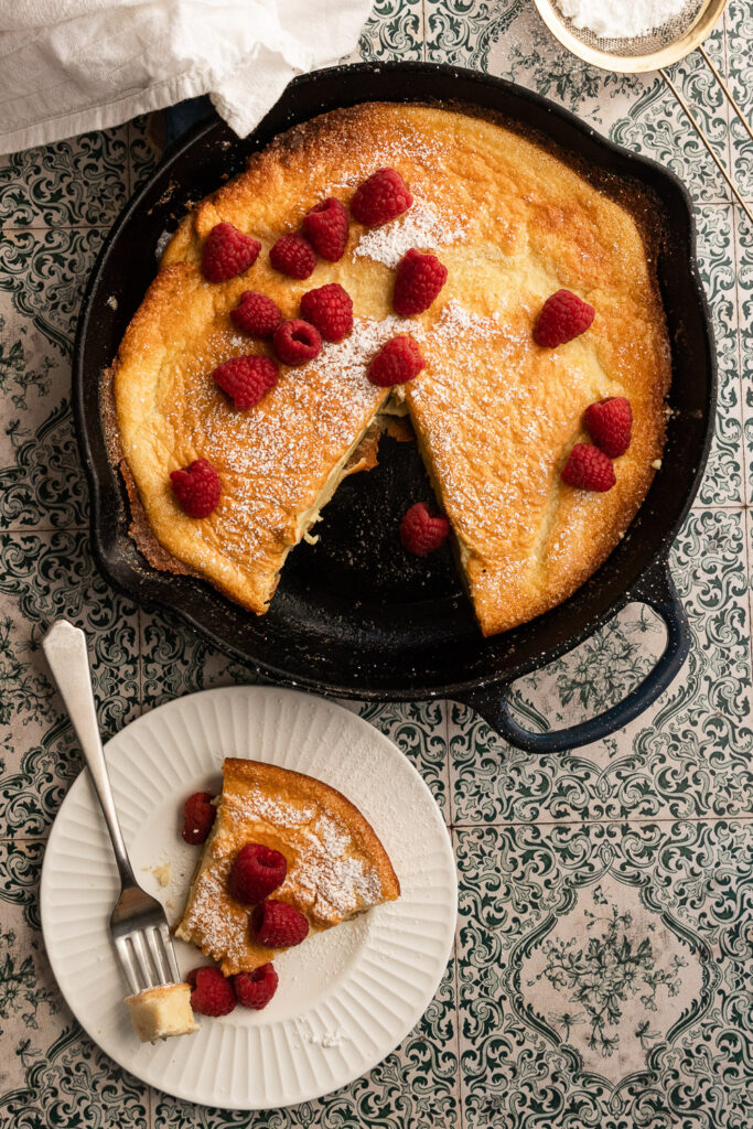 A sourdough Dutch baby, topped with raspberries and a dusting of powdered sugar.