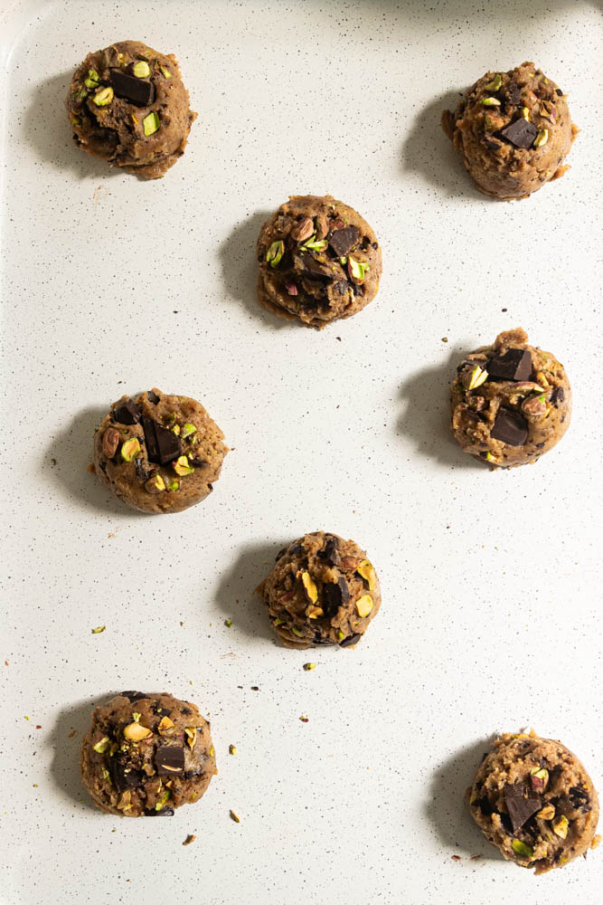 Cookie dough portions, all arranged on a baking sheet.