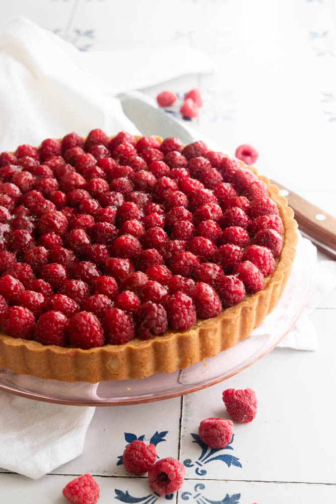 A raspberry almond tart in a golden brown curst and topped with fresh raspberries.