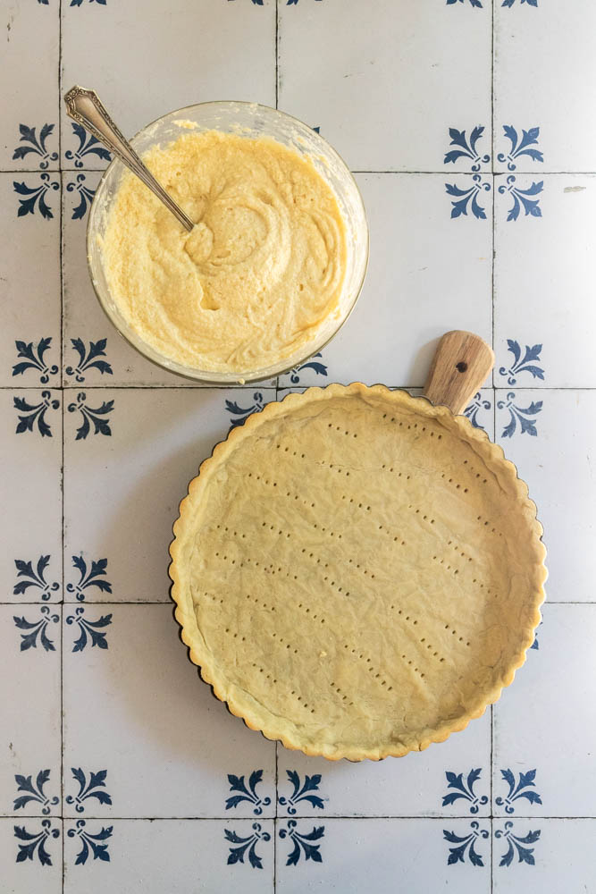 A parbaked crust and bowl of frangipane (almond cream) ready to add to it.