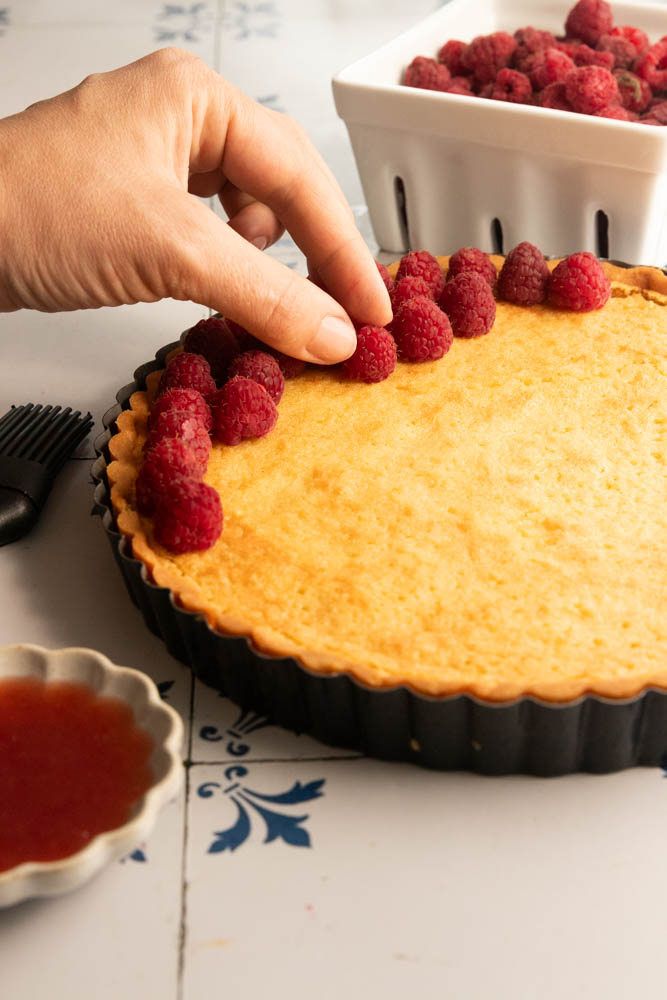 Adding the fresh raspberries to the top of the tart.