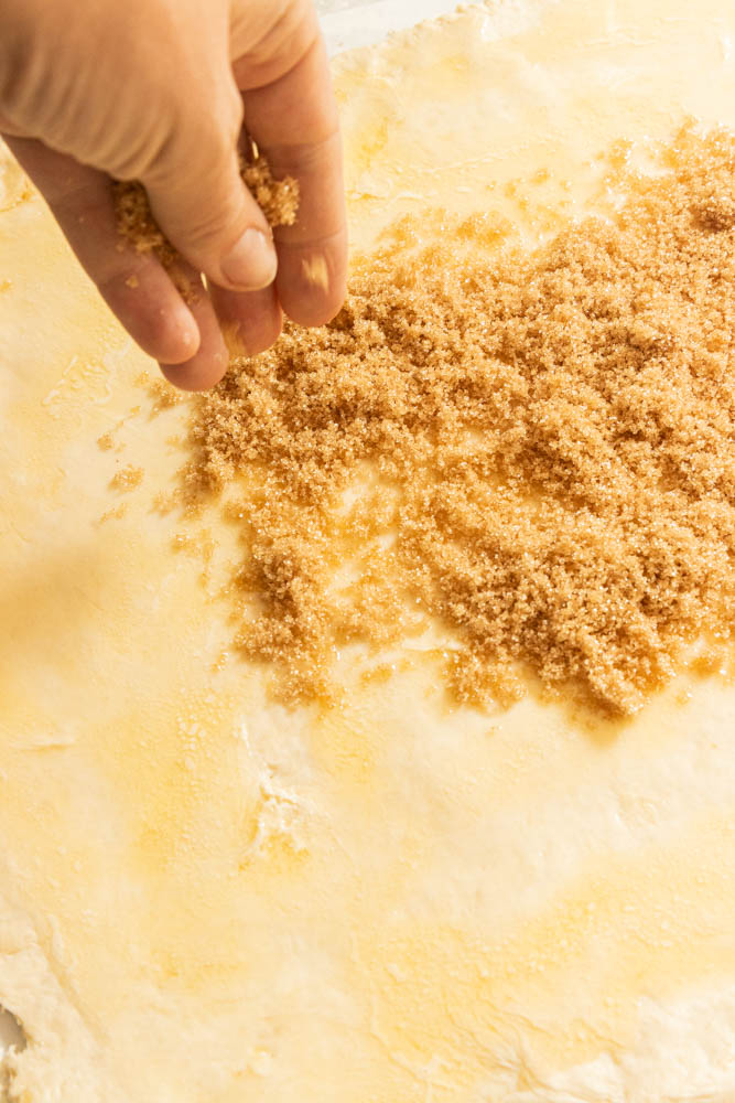 Sprinkling brown sugar over the rolled out dough.