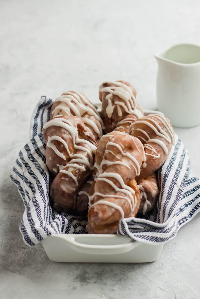 Cinnamon Roll Donuts -- Donut Twists in a pan with glaze drizzled over the top.