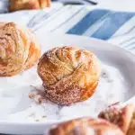 Warm, flaky cruffins (croissants and muffins in one) being rolled in sugar.