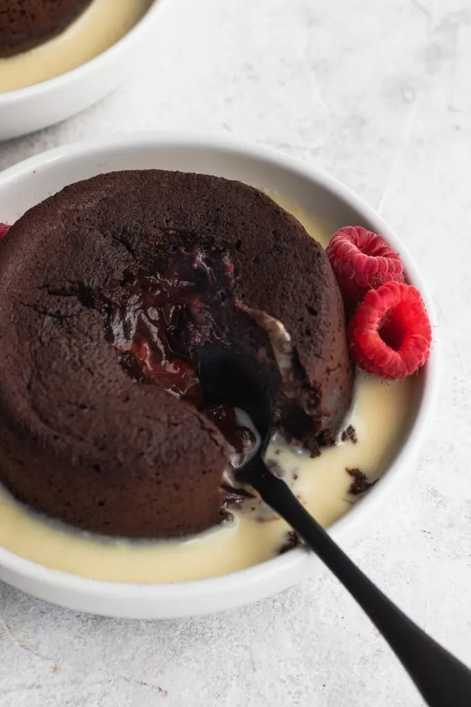 Raspberry Chocolate Lava Cakes with an oozing chocolate and raspberry center, garnished with creme anglaise and fresh raspberries