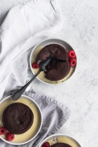 Raspberry Chocolate Lava Cakes with an oozing chocolate and raspberry center, garnished with creme anglaise and fresh raspberries