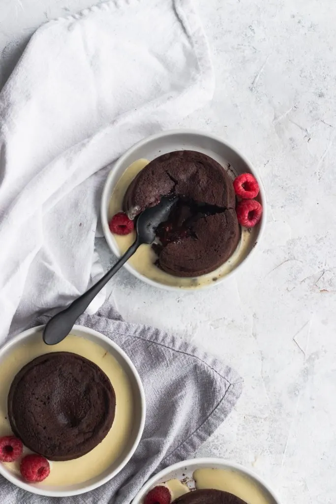 Raspberry Chocolate Lava Cakes with an oozing chocolate and raspberry center, garnished with creme anglaise and fresh raspberries