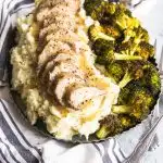 A platter of Dijon Pork Tenderloin piled on mashed potatoes and roasted broccoli on the side.