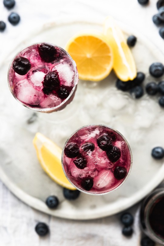 A flatlay with two glasses of sparkling blueberry lemonade