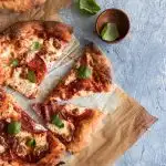 A sourdough crust pizza topped with mozzarella, slices of salami and pepperoni, and fresh basil leaves.