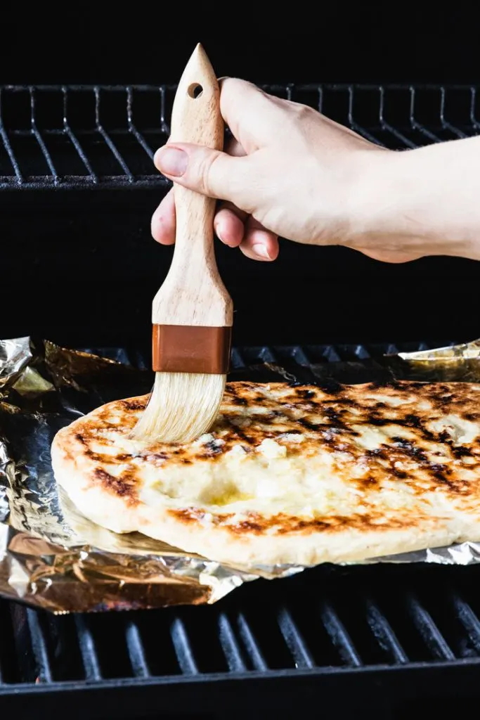 Brushing garlic butter on a grilled flatbread