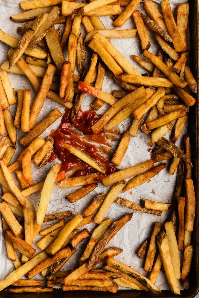A tray of crispy fried french fries with tomato ketchup in the center for dipping.