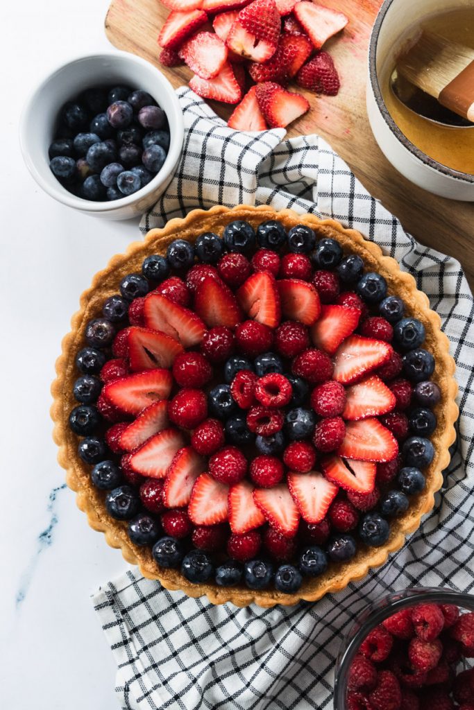 A tart with almond cream filling that's topped with beautifully arranged blueberries, raspberries, and strawberries.
