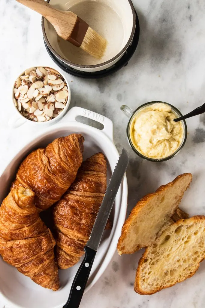 The assembled ingredients for almond croissants--day old croissants, almond cream filling, sliced almond, and sugar syrup.