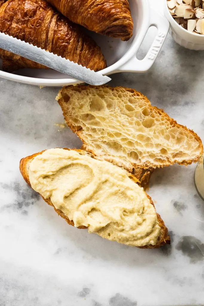 Almond croissant filling spread on half of a sliced croissant.