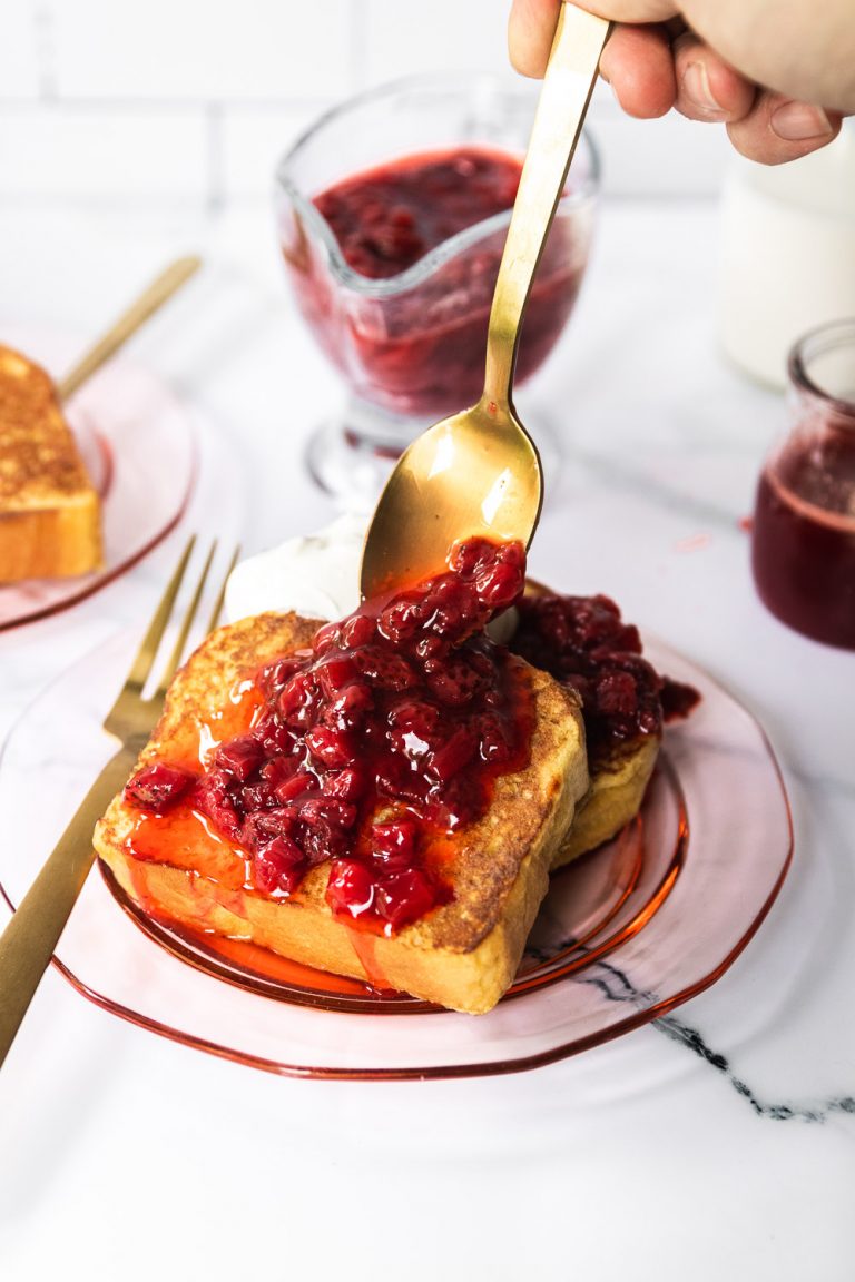 Homemade Strawberry Syrup being spooned over french toast with whipped cream