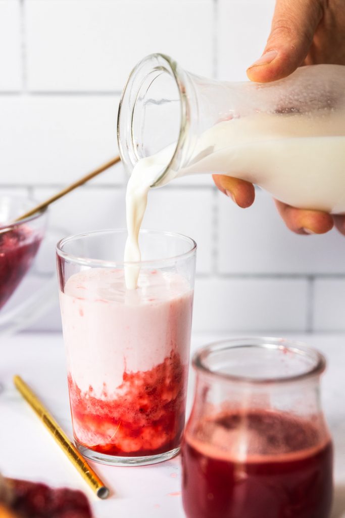 Coconut milk being poured into strawberry syrup