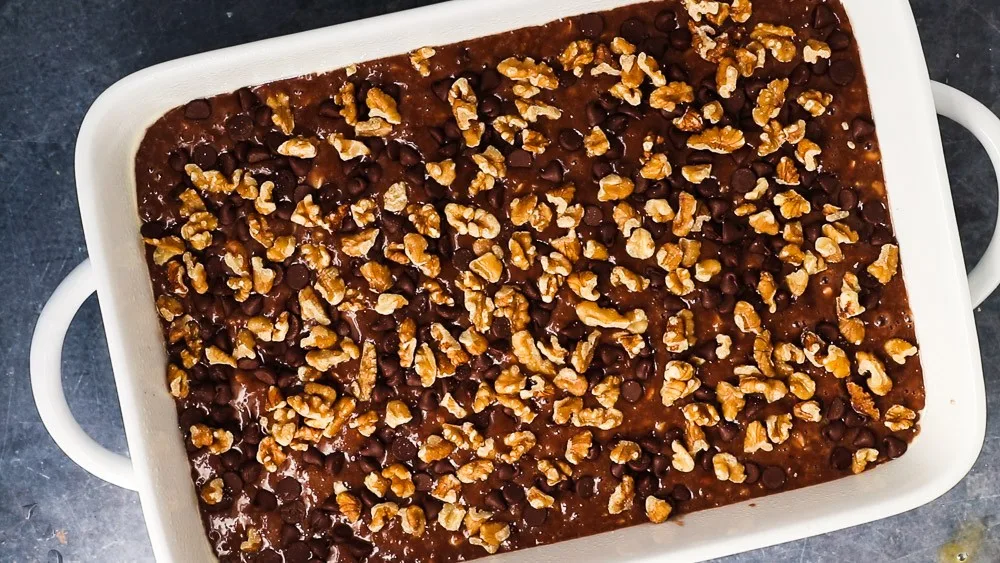 Pour the chocolate oatmeal cake batter into an oiled 9x13" baking pan and sprinkle the rest of the chocolate chips and the walnuts (if using) over the top.