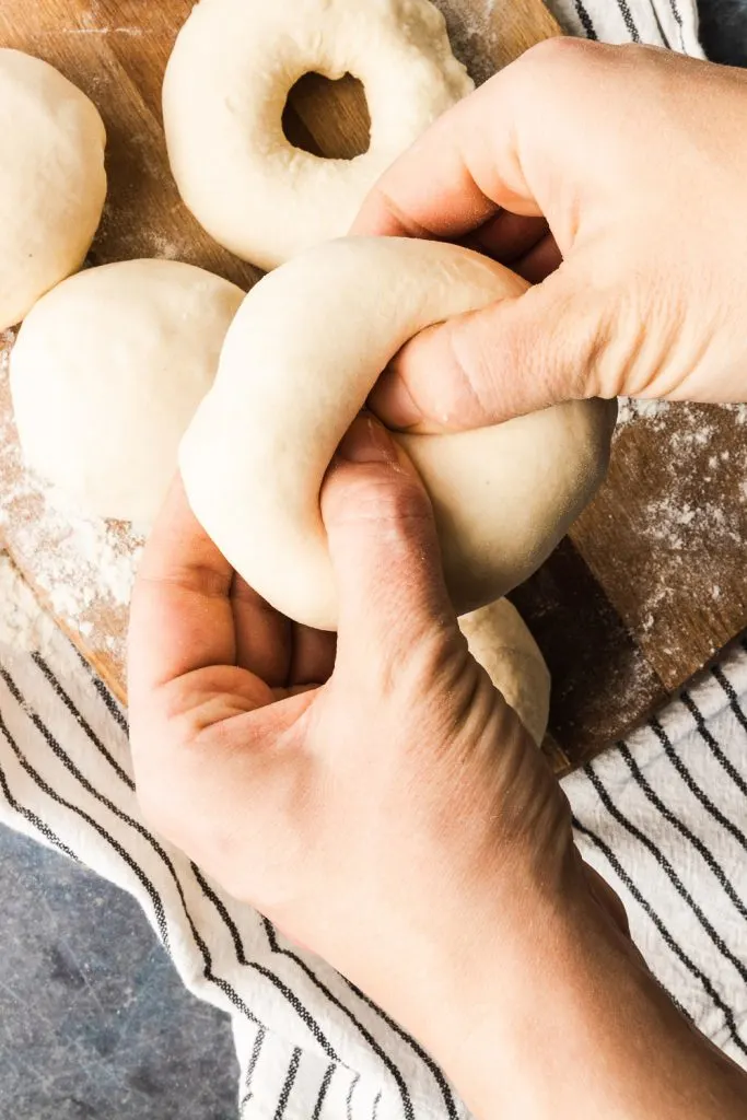 Poking a hole in the middle of each circle of dough with your thumbs.