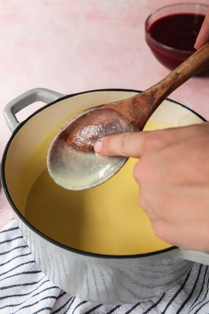 Drawing a finger through the custard on the spoon to make sure it's thick enough.