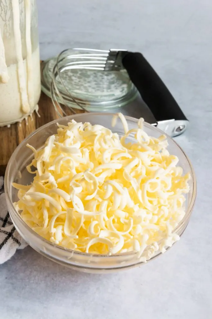 Take your stick or block of cold butter and grate it with a large-holed grater. Pop the grated butter into the freezer for about 10 minutes, then cut it into the dry ingredients until it's a clumpy, sandy mixture.