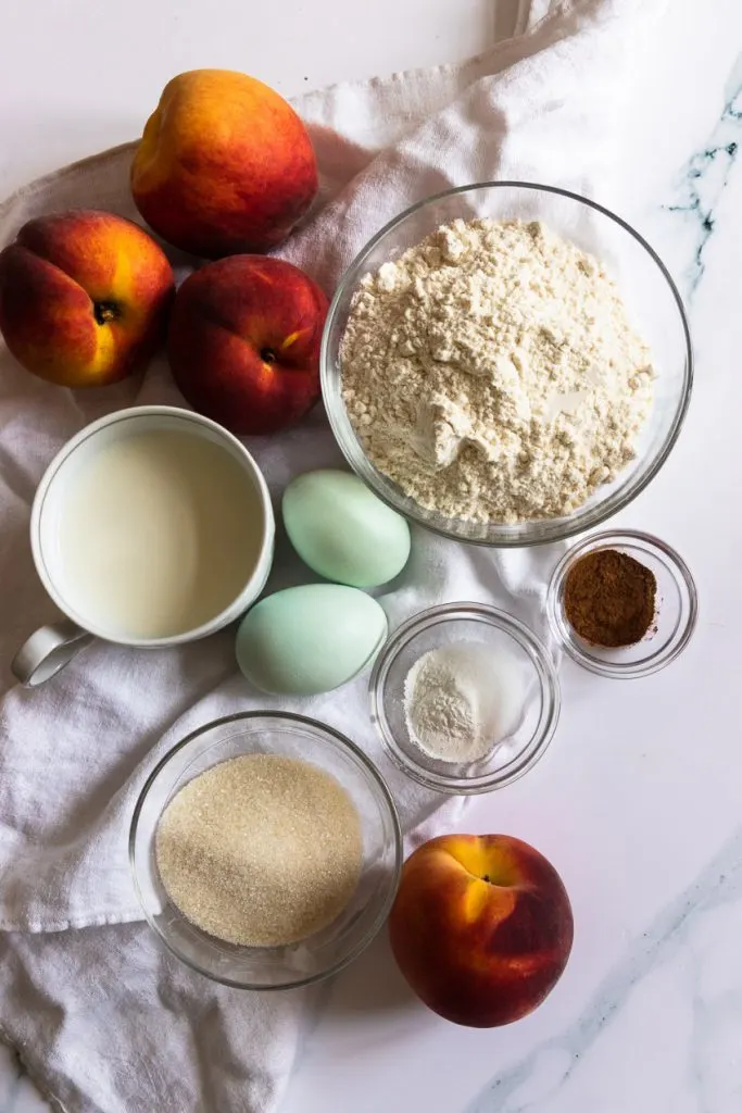 Easy peach fritter ingredients--flour, sugar,salt, baking powder, cinnamon, nutmeg, milk, eggs, and fresh peaches.